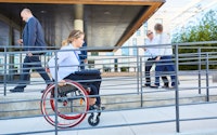 Disabled woman in a wheelchair on her way to work on a ramp to the office