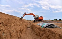 Excavator dig the trenches at a construction site. Trench for laying external sewer pipes. Sewage drainage system for a multi-story building. Civil infrastructure pipe, water lines.