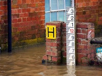 Flood waters surrounding a brick house and coming up to level 5 on a flood scale measure