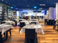 Modern restaurant interior with open kitchen and empty tables without any dining.