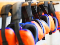 Row of orange ear muffs ear protection on a rack workplace health and safety