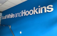 Scott White and Hookins logo on a branded blue wall inside the Winchester office