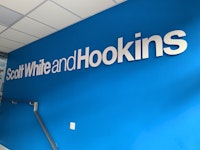 Scott White and Hookins logo on a branded blue wall inside the Winchester office