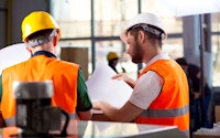 Male factory worker and supervisor reviewing documents