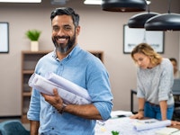 Portrait of male employee with blueprints in office