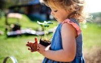 Small girl with dirty hands outdoors in garden sustainable lifestyle